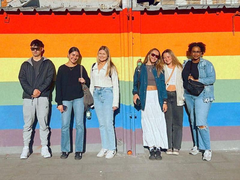 Ragazzi e ragazze davanti a un muro con i colori arcobaleno