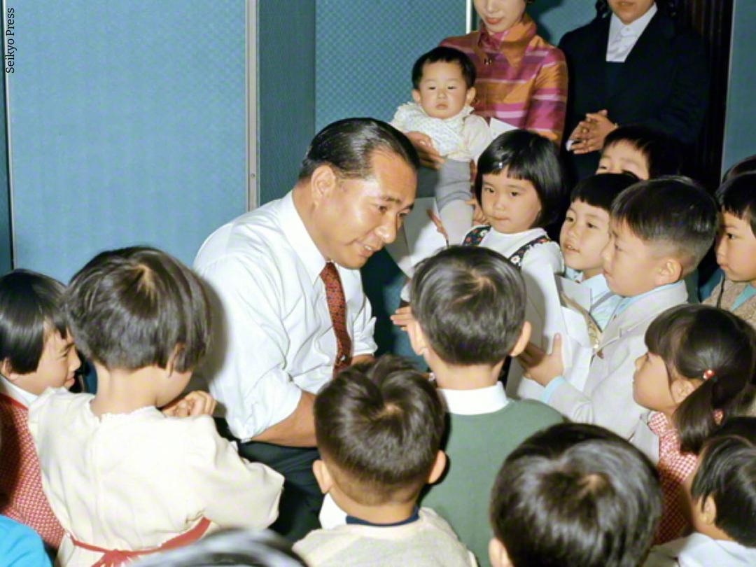 Daisaku Ikeda immerso in un gruppo di bambini e bambine