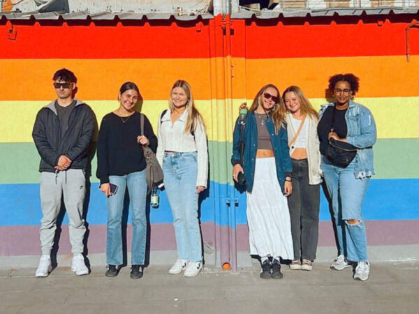 Ragazzi e ragazze davanti a un muro con i colori arcobaleno